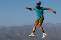 A model jumping in a classic cotton/poly 1968 swrve logo t-shirt in cyan.